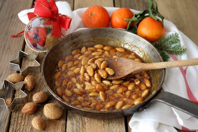 Caramello ambrato con mandorle in padella durante la preparazione del croccante di mandorle Caramello ambrato con mandorle in padella durante la preparazione del croccante di mandorle