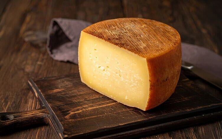 Pezzo di pecorino Carmasciano con crosta naturale e pasta giallo paglierino. pecorino di Carmasciano