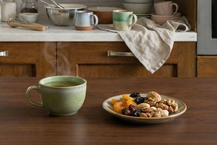 una tazza di tè verde e un piattino di frutta secca