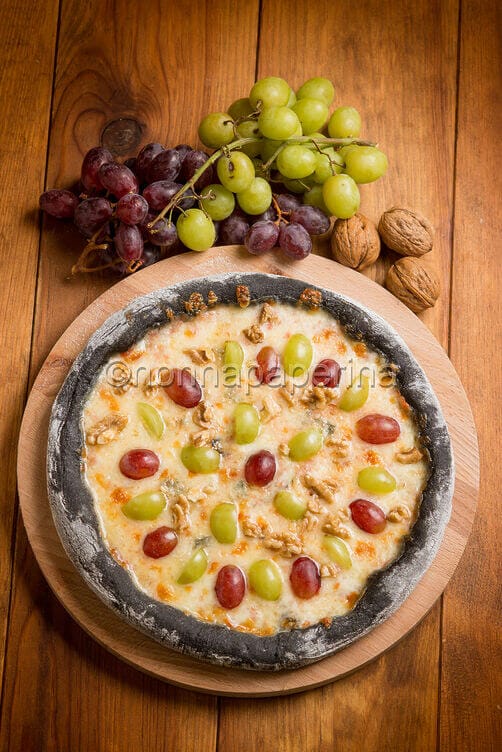 Pizza nera con uva e taleggio