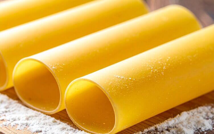 sfoglia per cannelloni appena stesa, texture liscia e gialla, polvere soffice di farina, sfondo in legno naturale cannelloni pronti da farcire