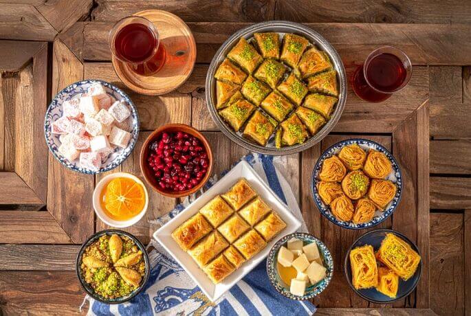 dolci turchi :baklava , lokum (rahat), tulumba şekerpare revani, kunefe coppette di sütlaç e kazandibi, una ciotola di aşure con frutta secca e chicchi di melograno, e fili di pişmaniye